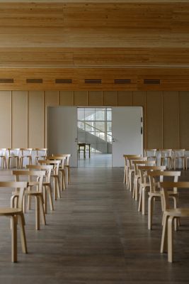 Spacious minimalist concert hall interior featuring rows of wooden chairs.