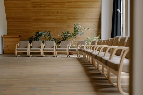 Spacious modern conference hall with wooden chairs and potted plants, perfect for events.