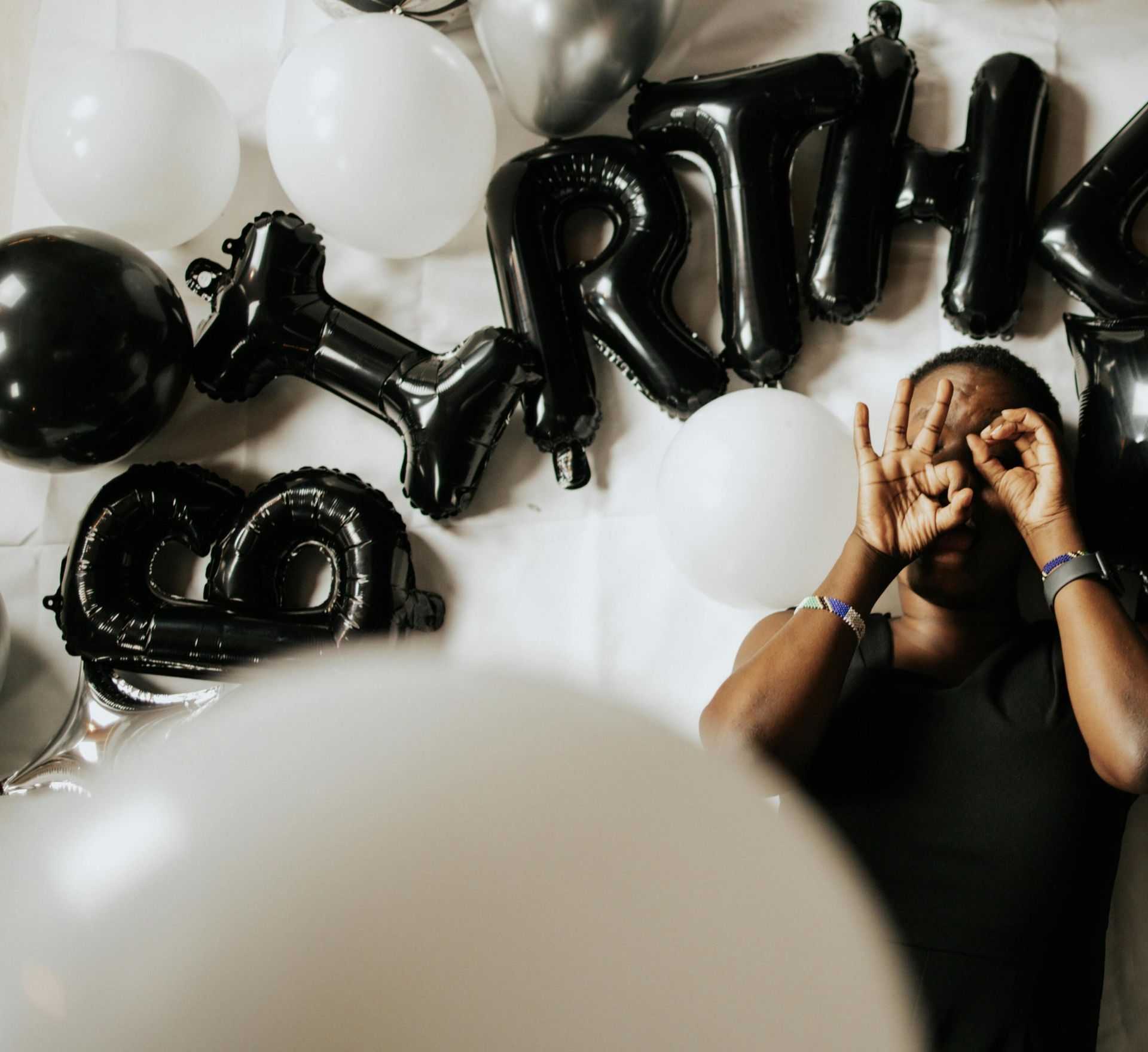 Top view of a man celebrating birthday surrounded by black and white balloons.