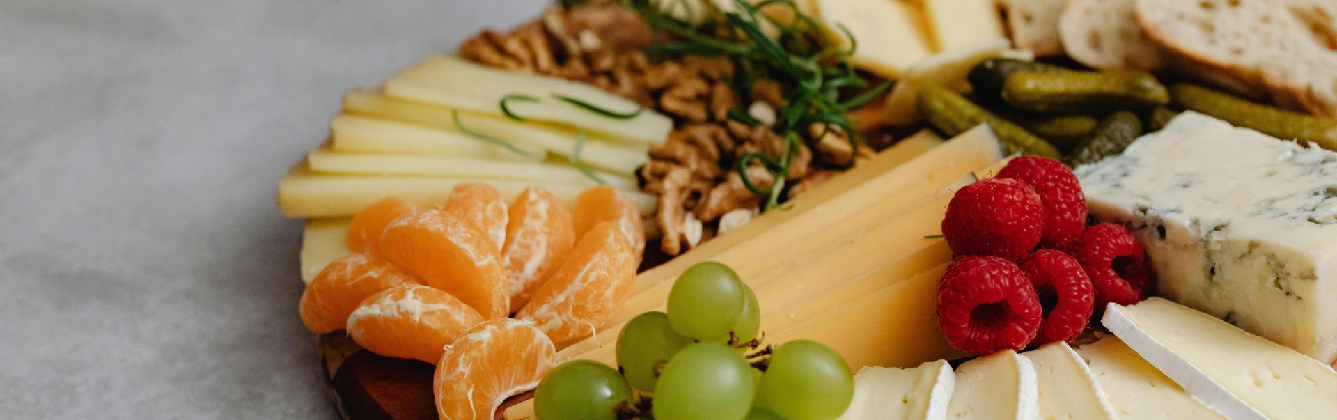 A visually appealing cheese platter with an assortment of fruits, nuts, and crackers.