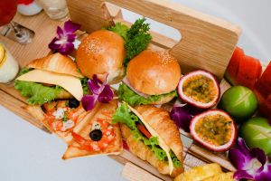 A vibrant breakfast tray featuring croissants, burgers, and tropical fruits, perfect for a delicious morning.