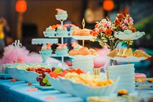 Colorful dessert table featuring a variety of fruits, cakes, and floral decor, ideal for celebrations.