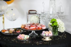 A beautifully arranged table with various colorful desserts and floral decorations, perfect for celebrations.