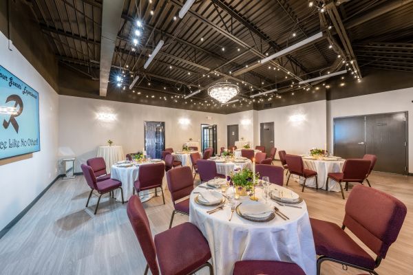 Spacious modern conference hall with wooden chairs and potted plants, perfect for events.